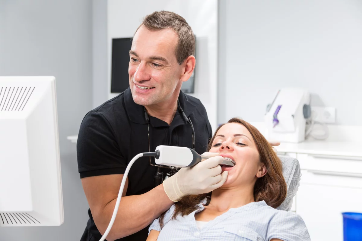 Dentist scanning patient's teeth with CEREC (Chairside Economical Restoration of Esthetic Ceramics) scanner